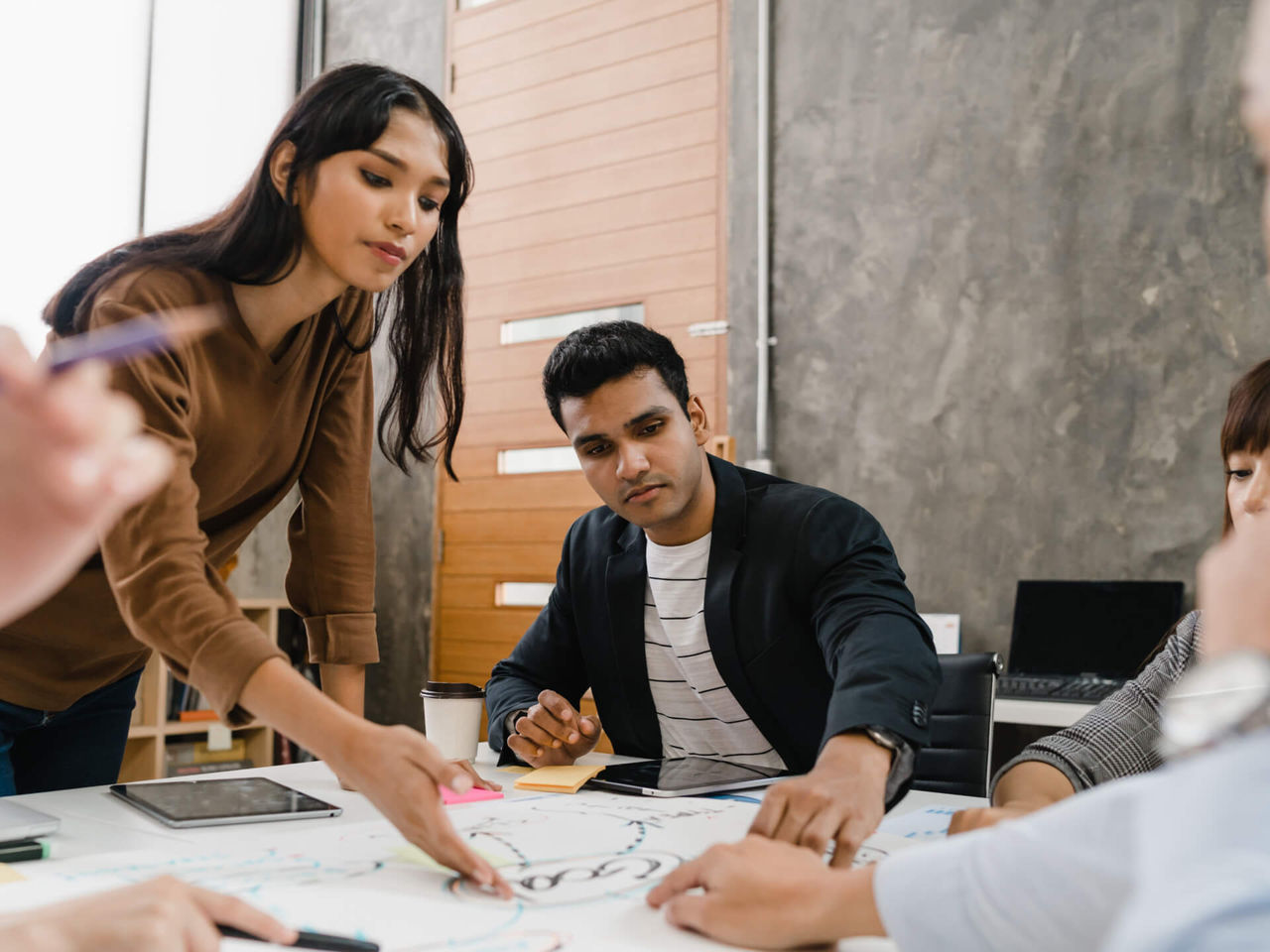 A group of people in a business meeting looking at a drawing.